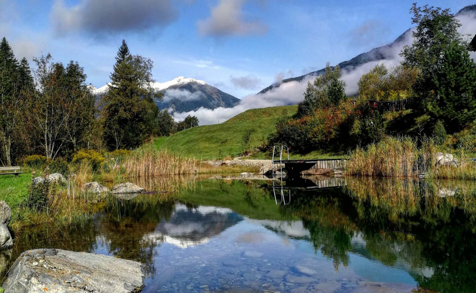 Naturlandschaft mit Badeteich und Bergen im Hintergrund